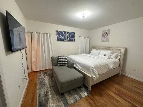 een slaapkamer met een bed, een stoel en een televisie bij Deluxe 3 Bedroom EWR airport home in Elizabeth