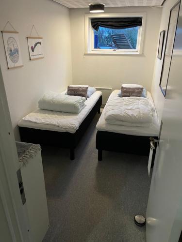 two beds in a small room with a window at Happy Fisherman BnB in Aalborg