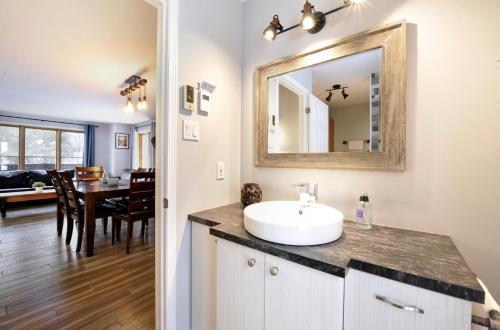 a bathroom with a sink and a mirror and a dining room at 16 Chemin Alpin in Stoneham
