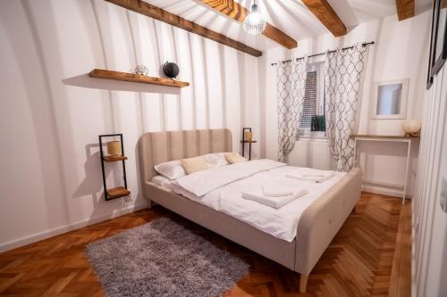 a bed in a room with white walls and wooden floors at Middle Apartments in Braşov