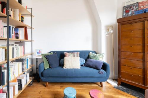 un sofá azul en una sala de estar con estanterías en Nice apartment in the heart of Paris - Welkeys en París
