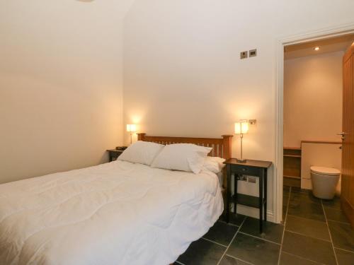 a bedroom with a white bed and two night stands at The Old Dairy in Pwllheli