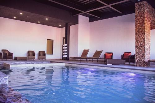 una piscina en un hotel con sillas y mesas en Hotel María Bonita Chihuahua en Chihuahua