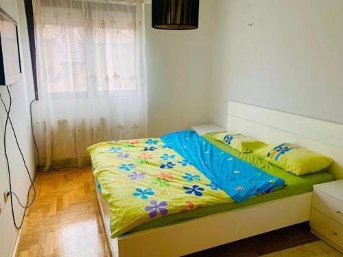 1 dormitorio con 1 cama con un edredón colorido en Cozy city center apartment, en Prizren