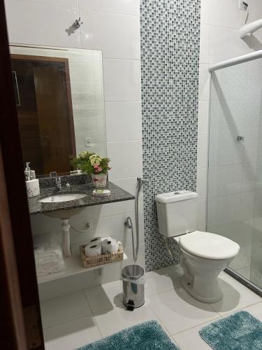 a bathroom with a toilet and a sink and a mirror at Chalé Ipê Branco in Pedra Azul