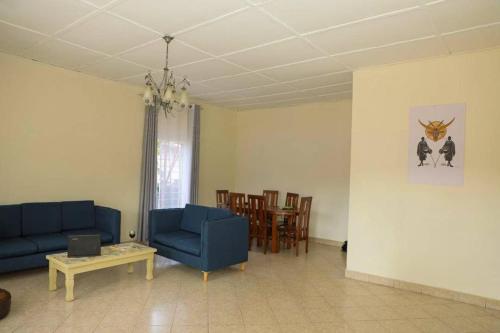 sala de estar con sofás azules, mesa y sillas en Inkindi House en Kigali