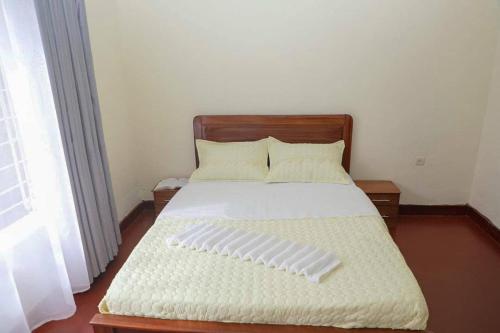 1 dormitorio con 1 cama con cabecero de madera en Inkindi House en Kigali