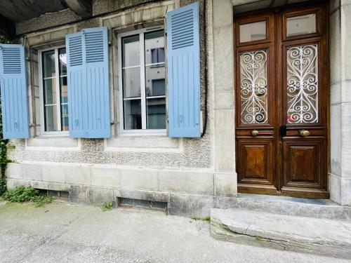 um edifício com persianas azuis e uma porta de madeira em LE CAUBOUS Plein centre T2 calme avec chambre, balcon et cuisine équipée em Bagnères-de-Bigorre