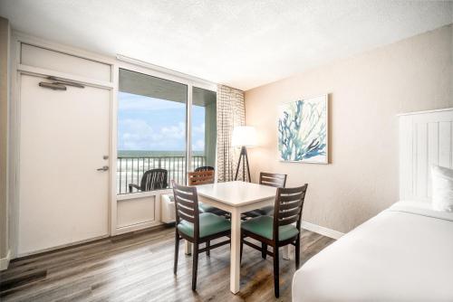 a bedroom with a table and chairs and a bed at Perry's Ocean-Edge Resort in Daytona Beach