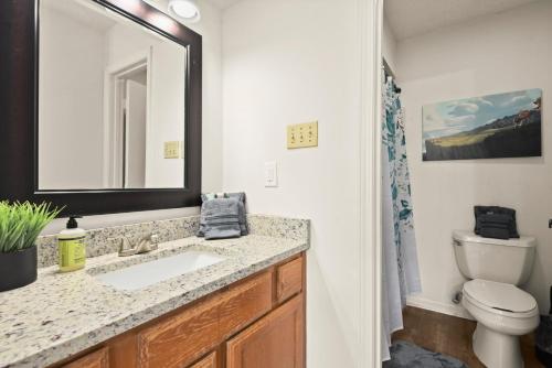 a bathroom with a sink and a toilet and a mirror at LSU 2Bed/2Bath Angel Studios Condo *NEW* in Baton Rouge