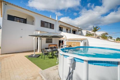 a villa with a swimming pool in front of a house at Host Wise - Sunny Spacious House - Terrace & Free Parking in Lagoa
