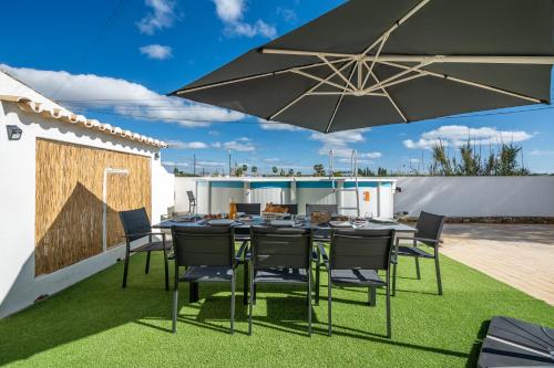 a patio with a table and chairs and an umbrella at Host Wise - Sunny Spacious House - Terrace & Free Parking in Lagoa