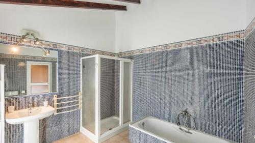 Encinas RealesにあるCasa de Royal Oaks Encinas Reales by Ruralidaysの青いタイル張りのバスルーム(シンク、バスタブ付)