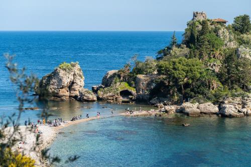 a group of people on a beach in the water at Isola Bella - Rooms il Pescatore in Taormina