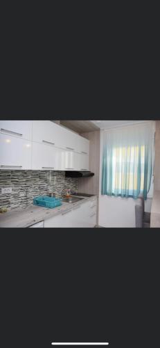 a kitchen with white cabinets and a blue curtain at Romantika 3 in Ostrovo