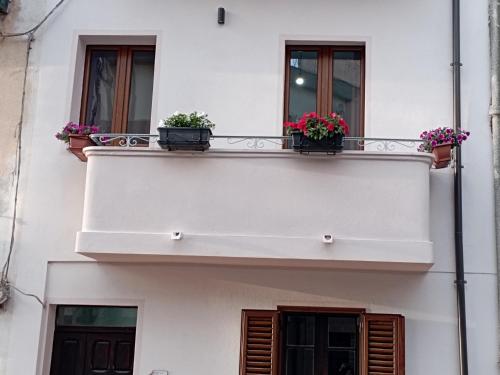 un edificio blanco con tres macetas en un balcón en CASA DEL CORSO, en Dorgali
