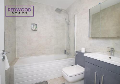 a bathroom with a tub and a toilet and a sink at Spacious Serviced Apartment for Contractors and Families, FREE WiFi & Netflix by REDWOOD STAYS in Farnborough