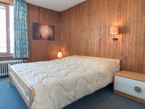 ティーニュにあるAppartement Tignes, 2 pièces, 5 personnes - FR-1-449-167の大きなベッドと木製の壁が備わるベッドルーム1室が備わります。