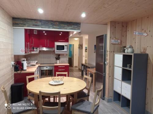 une cuisine avec des placards rouges et une table en bois dans l'établissement Appartement 3 pièces rénové, proche des pistes à Tignes - FR-1-449-60, à Tignes