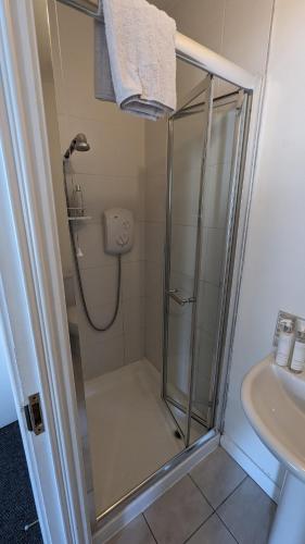 a shower with a glass door next to a sink at Cosy Fermanagh Home - The Cosy Beech in Lisnaskea