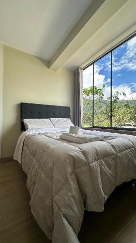 a bedroom with a large bed with a large window at La Herencia - Oxapampa in Oxapampa