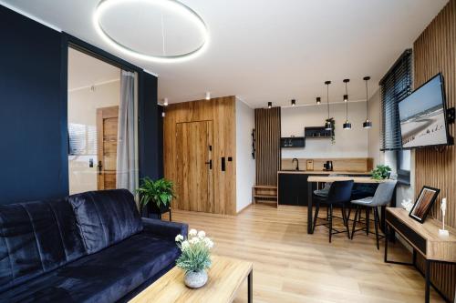 a living room with a black couch and a kitchen at Apartamenty i Pokoje Złote Piaski in Jastrzębia Góra