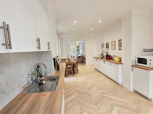 une cuisine avec des armoires blanches et un plancher en bois dans l'établissement La maison élégante, chambre proche gare et centre de Brunoy, à Brunoy