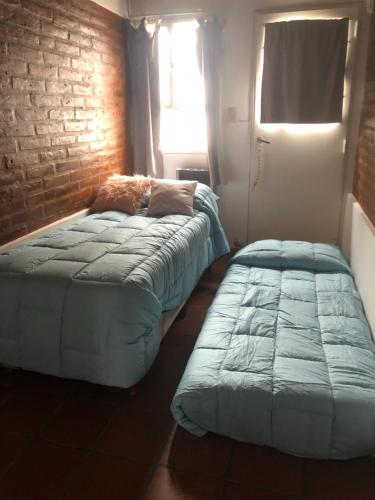 2 Betten in einem Zimmer mit Ziegelwand in der Unterkunft Mamama’s House in Puerto Madryn