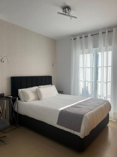 a bedroom with a large bed and two windows at Plaza de España Boutique Apartment in Nerja
