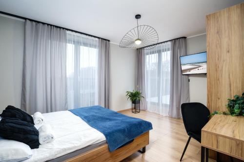 a bedroom with a bed and a desk and windows at Apartamenty i Pokoje Złote Piaski in Jastrzębia Góra