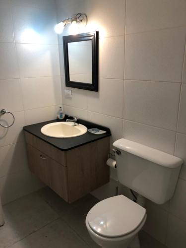 ein Badezimmer mit einem WC, einem Waschbecken und einem Spiegel in der Unterkunft Mamama’s House in Puerto Madryn