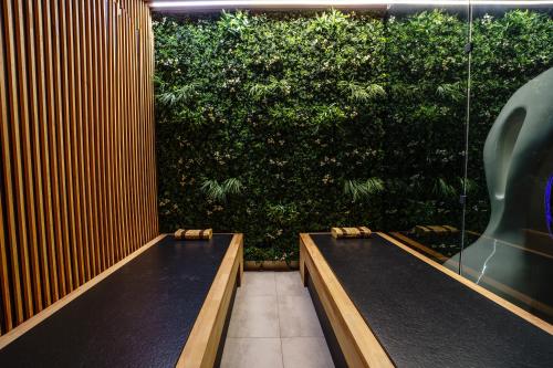 two benches in a room with a green hedge at Apartamenty i Pokoje Złote Piaski in Jastrzębia Góra