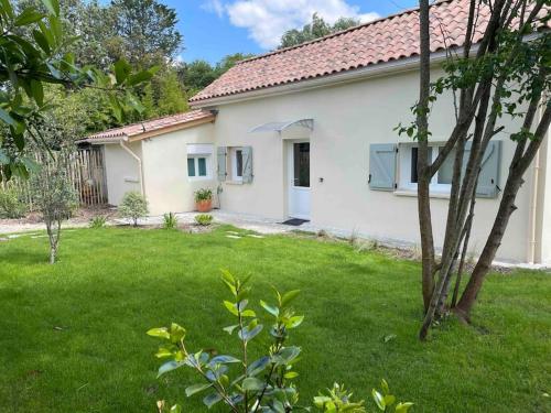 uma casa branca com um quintal com relva verde em Petite maison avec jardin au calme em Floirac