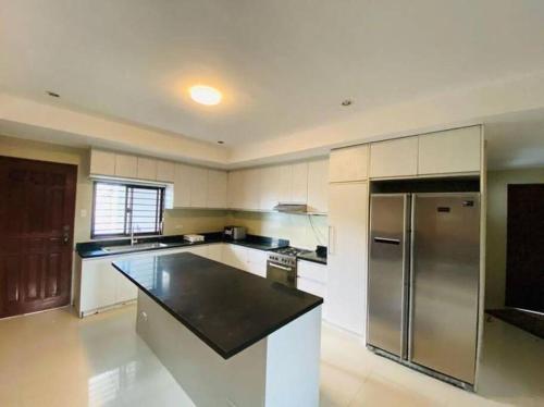 a large kitchen with white cabinets and stainless steel appliances at SpittlerVilla in Talisay
