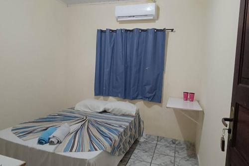 ein kleines Zimmer mit einem Bett mit einem blauen Vorhang in der Unterkunft Casa para Família in Porto Seguro