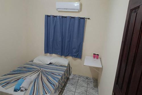 ein kleines Zimmer mit einem Bett und einem blauen Vorhang in der Unterkunft Casa para Família in Porto Seguro