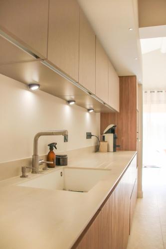 - une cuisine avec des comptoirs blancs et un évier dans l'établissement Villas Les Plaines en Provence, à Maillane