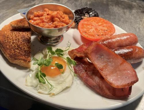a plate of breakfast food with eggs sausage and toast at The Half Moon Inn Rushall IP21 4QD in Pulham Saint Mary the Virgin