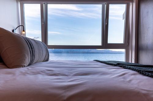 1 dormitorio con 1 cama y ventana grande en Lake Inn - Departamentos con costa de Lago en San Carlos de Bariloche