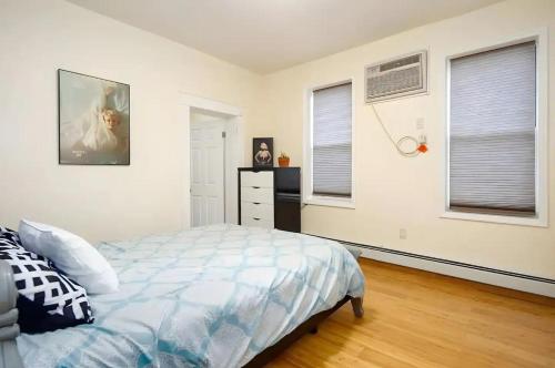 a bedroom with a bed and a dresser and two windows at Skyline View 20 minutes to Time Square #1 in West New York
