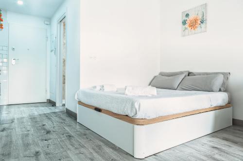 - un lit blanc dans une chambre blanche dotée de parquet dans l'établissement Apartamento Brisa Playa, à Aguadulce