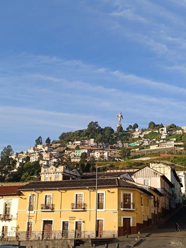 a yellow building with a statue on top of a hill at Hotel Colonial - Casa Francisco in Quito