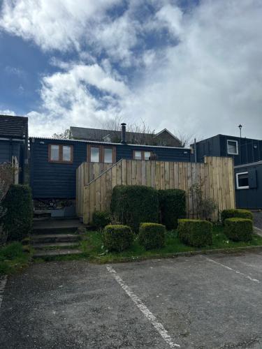 a house with a fence next to a parking lot at Hafod Shepherd Hut in Aberystwyth