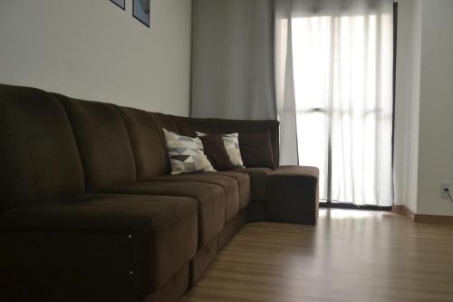 a brown couch in a living room with a window at Refúgio em Pelotas Com NF-E in Pelotas