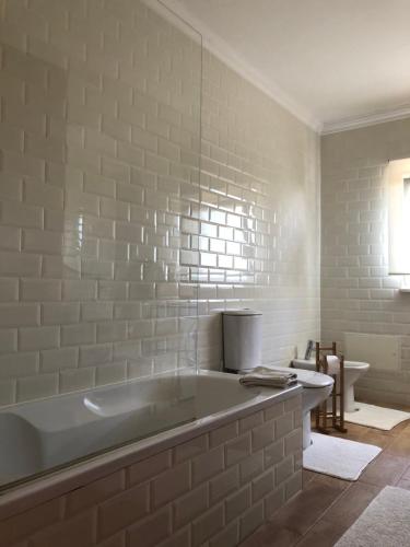 a white bathroom with a tub and a toilet at Moinho do Avô in Torres Vedras