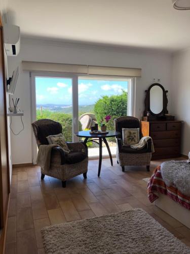 a living room with a table and chairs and a large window at Moinho do Avô in Torres Vedras
