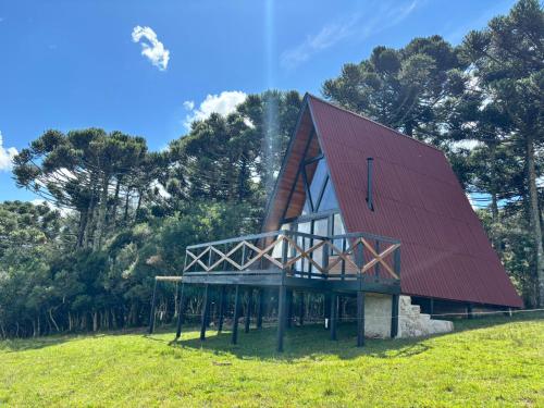 dom z czerwonym dachem na zielonym polu w obiekcie Chalés Corucacas w mieście Cambará