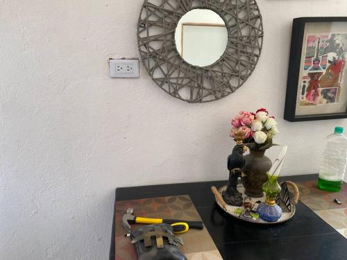 Hermoso apartamento, acogedor. في Mompós: طاولة مع مرآة و مزهرية مع الزهور عليها