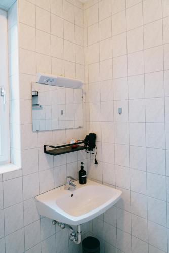 a white sink in a white tiled bathroom at Mountain View Salzburg - SELF CHECK-IN - Apartments in Grödig
