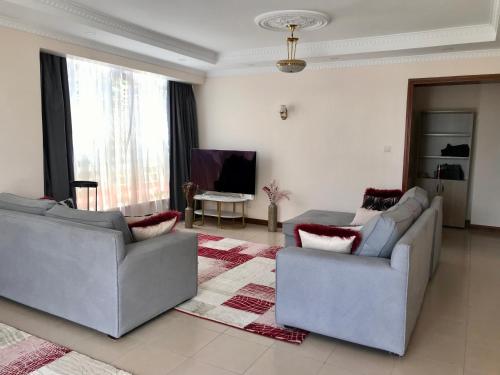 ein Wohnzimmer mit 2 Sofas und einem TV in der Unterkunft CASBAH HOMES in Nairobi